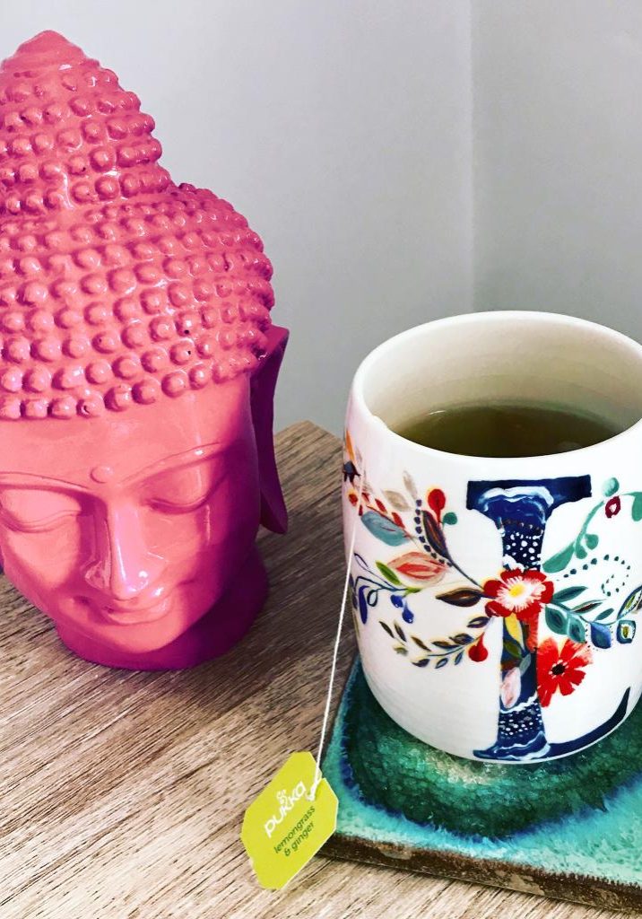 Relaxing desk scene, buddha head and cup of herbal tea